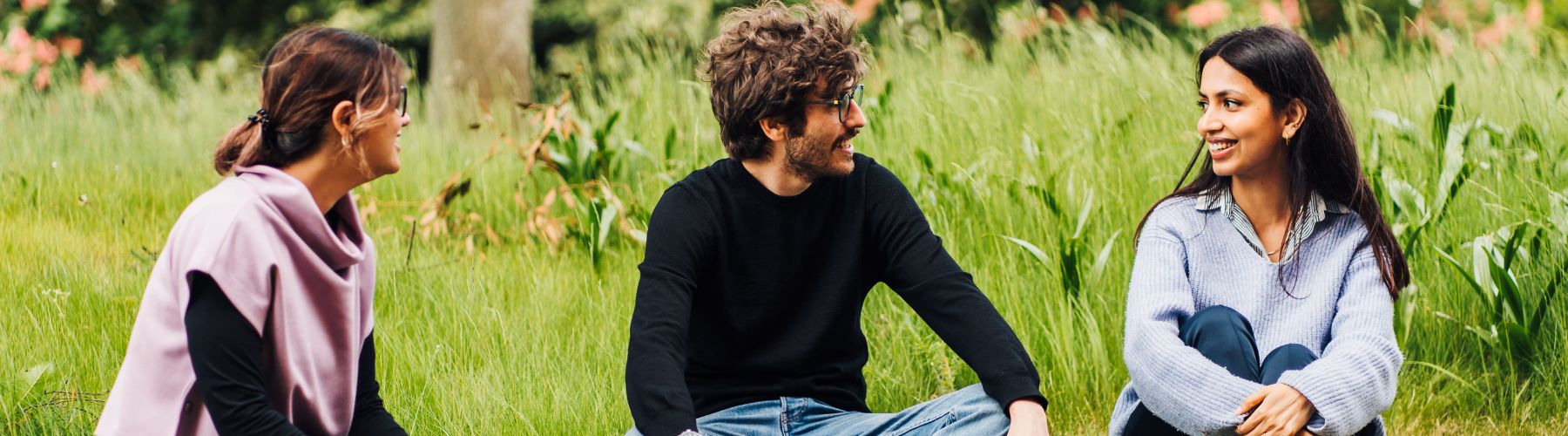 two students sitting on grass talking