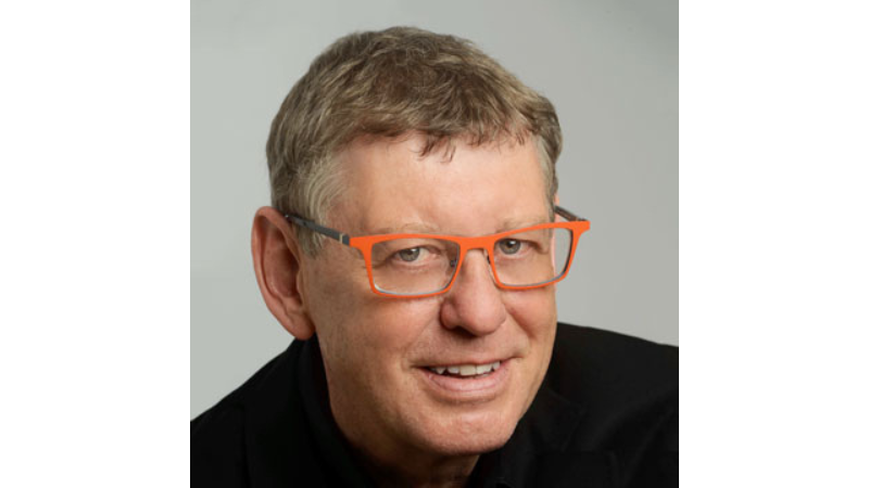 white male with red glasses and in a blue shirt