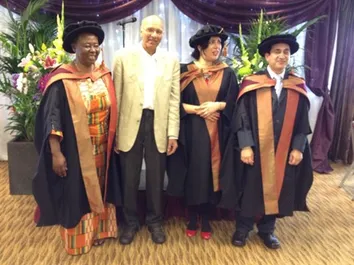 3 students in their graduation robes with one of our academic professors
