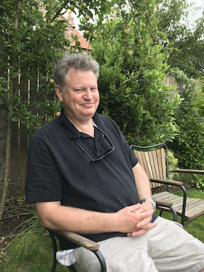Dr Timothy J. Sinclair sitting and smiling in his garden