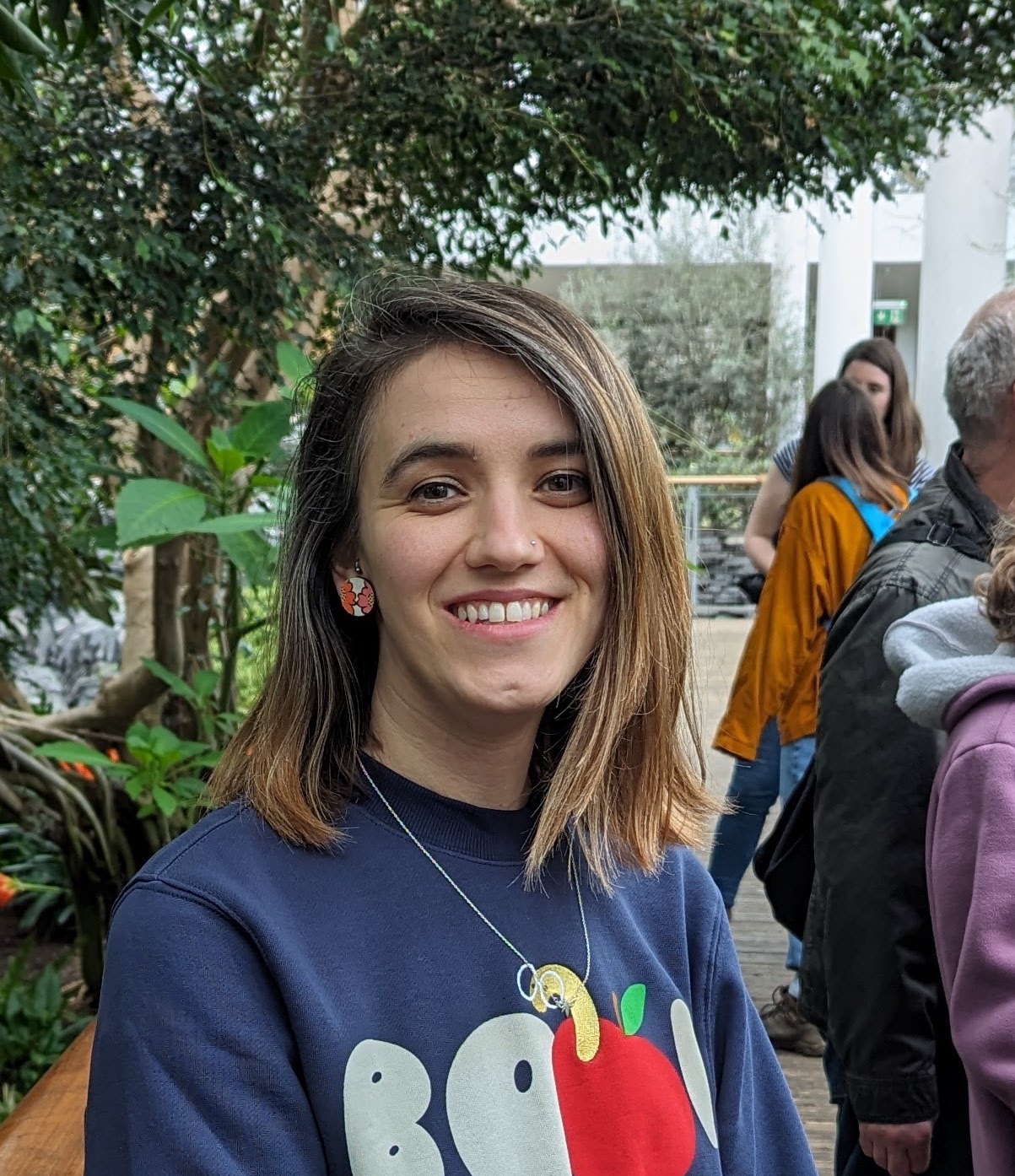 A headshot of a smiling woman in front of a background of plants