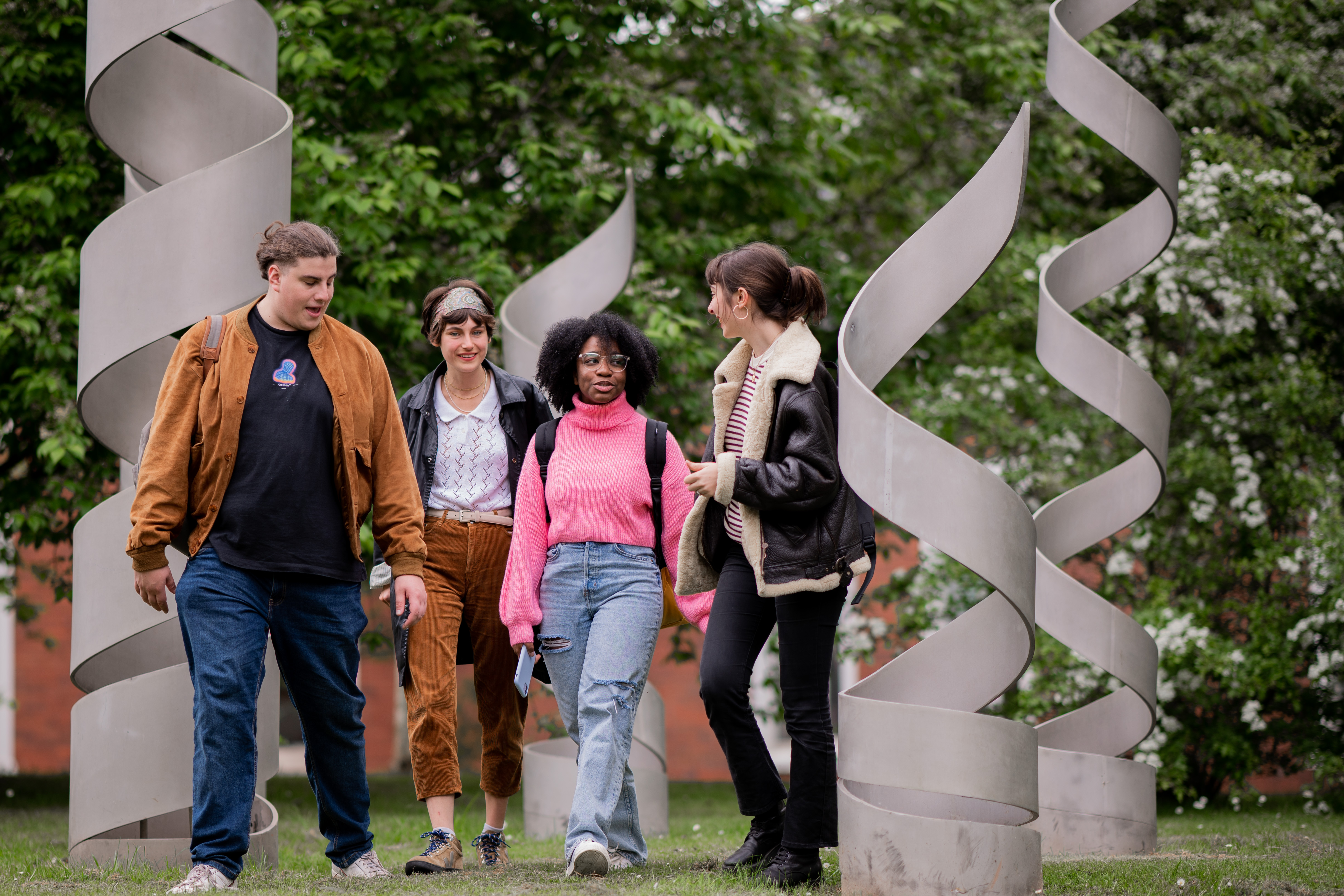 Four postgraduate research students walk through a spiral sculpture at the University of Warwick