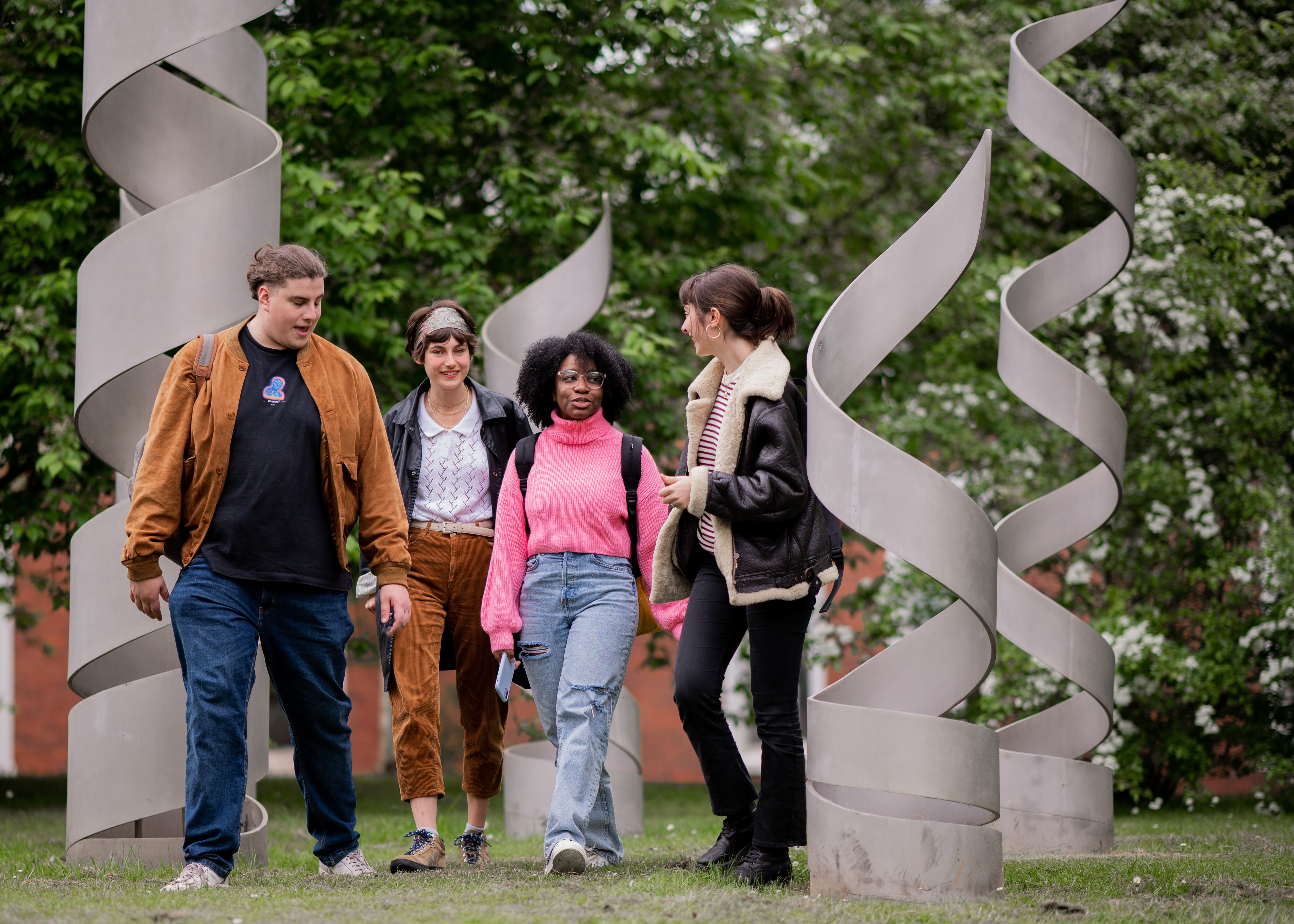 Four postgraduate research students walk through a spiral sculpture at the University of Warwick