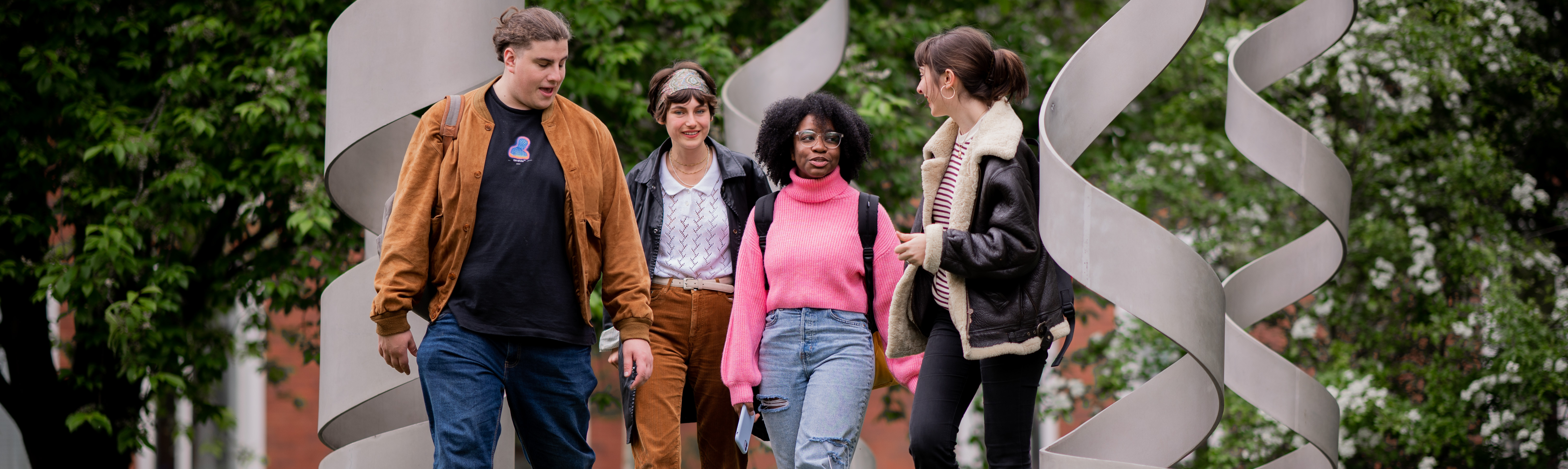 four postgraduate philosophy students walk through a sculpture on campus at the University of Warwick