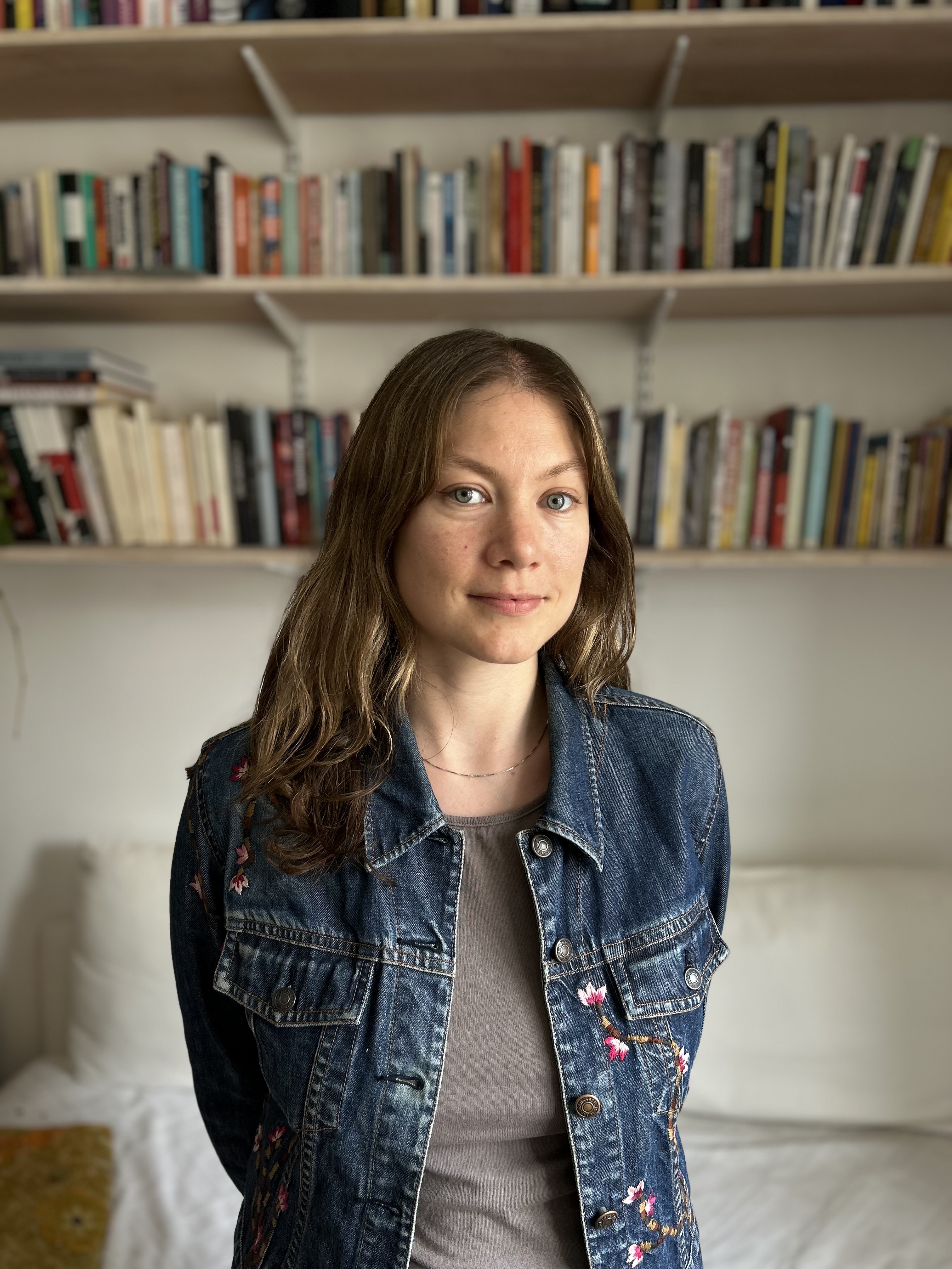 Gala Rexer stands in front of a bookcase looking at the camera