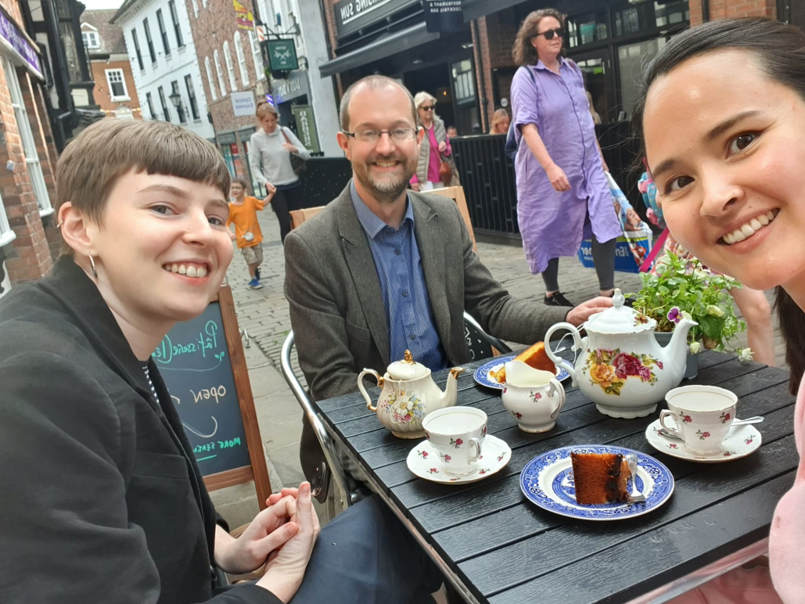 Three people eating cake and drinking tea