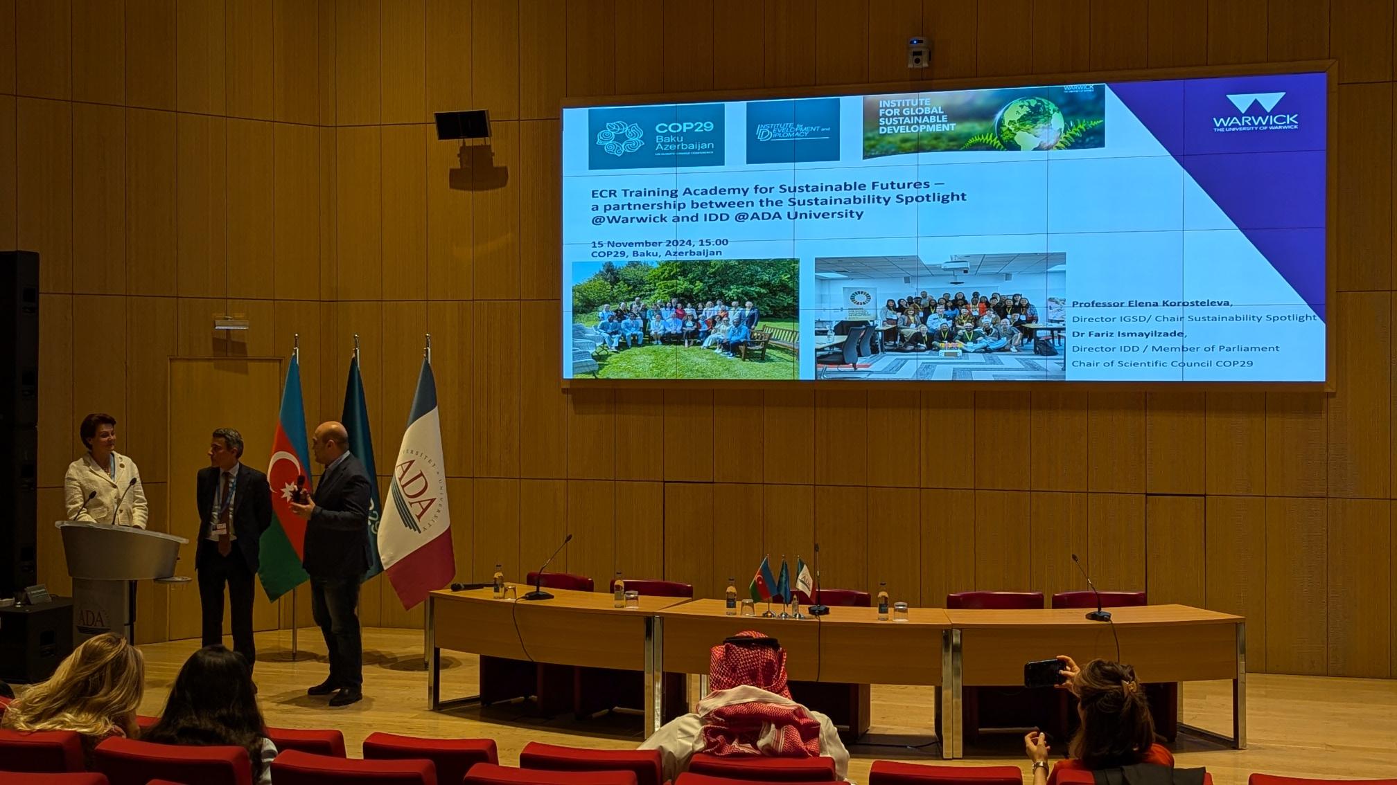 Image of the presentation stage at COP, with a large PowerPoint from Warwick featured on the screen.