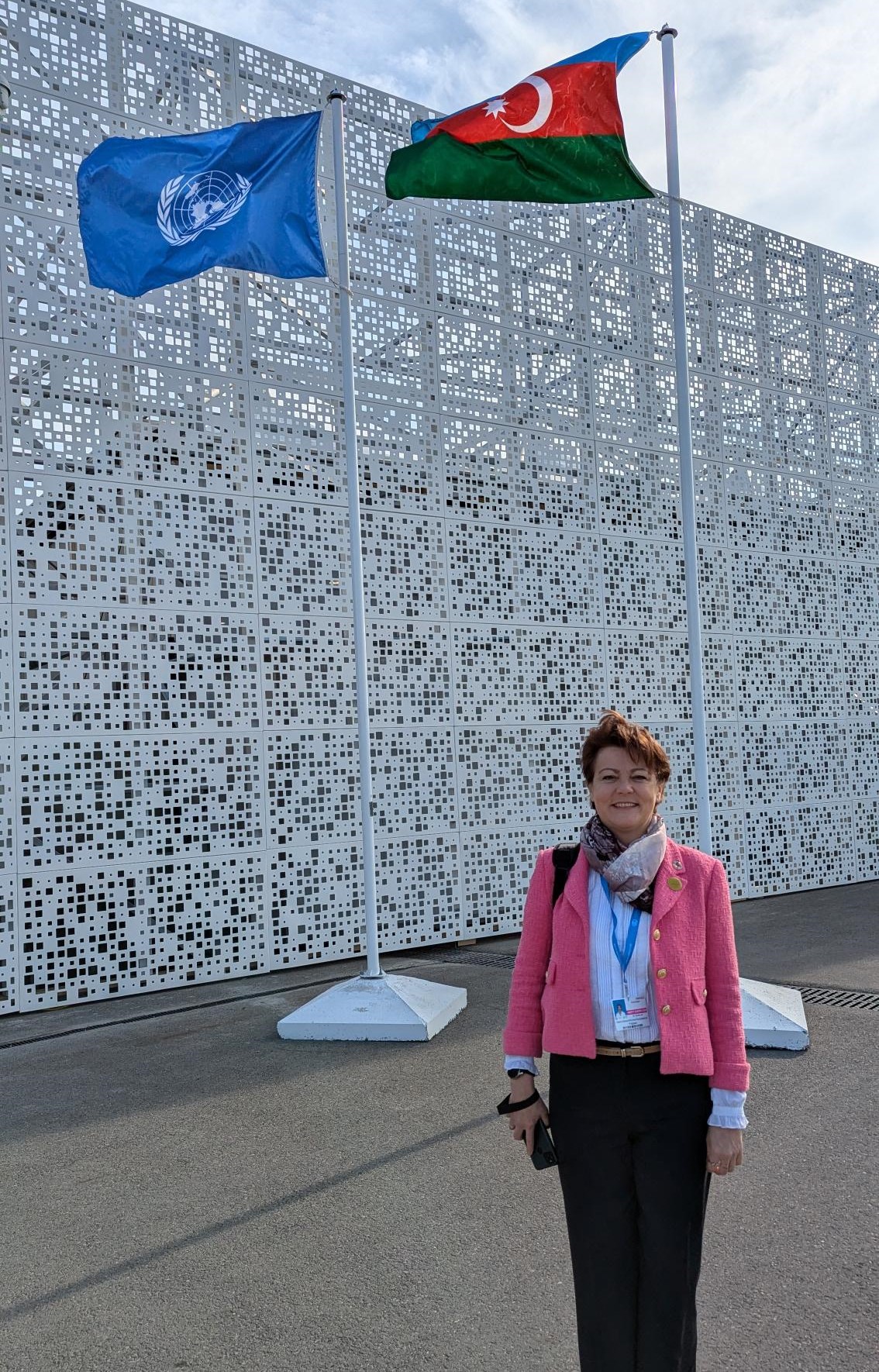 Image of Elena at Cop, smiling in front of flags