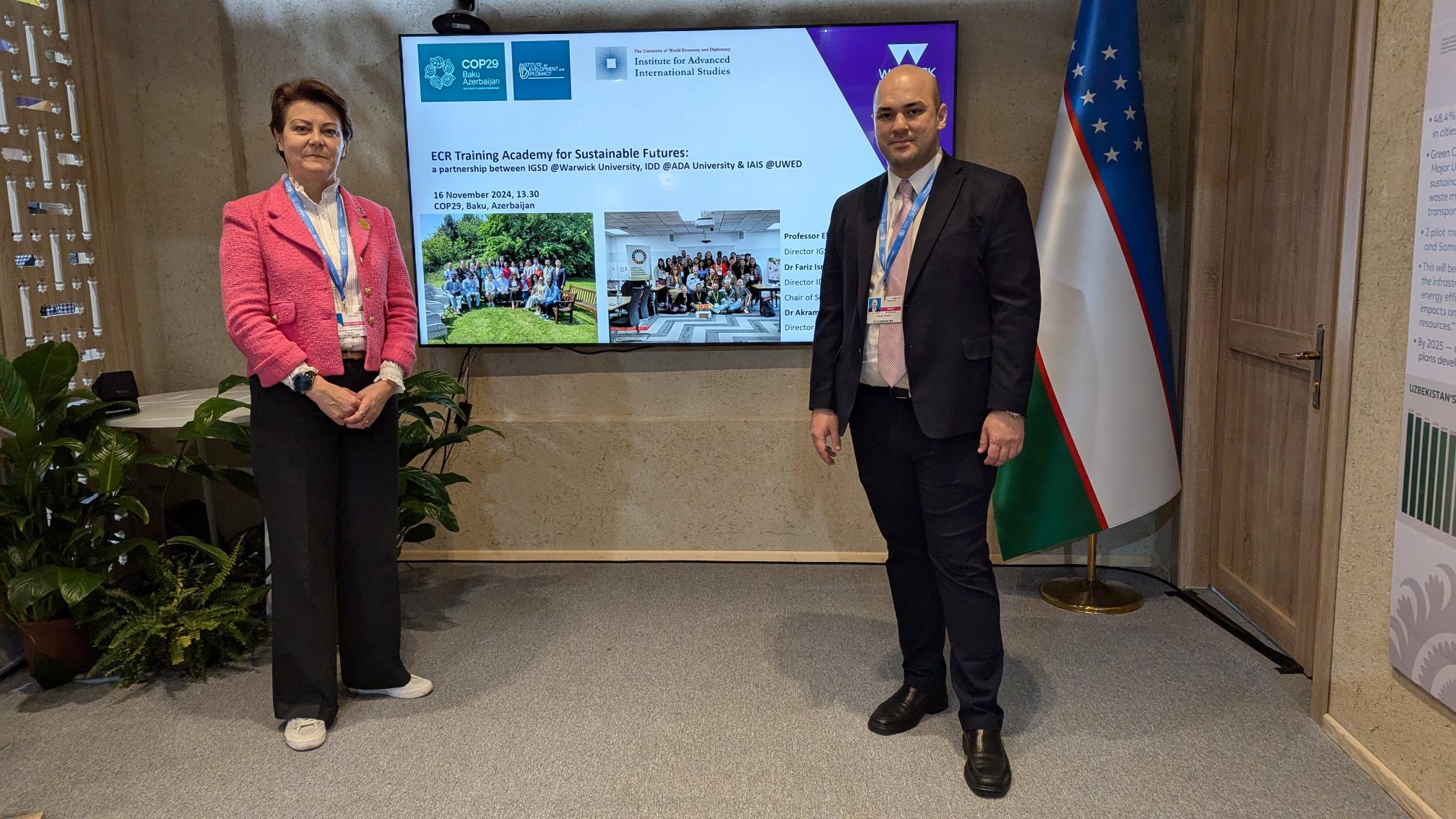 Image of Elena at the COP event, wearing a pink jacket and standing next to another attendee.