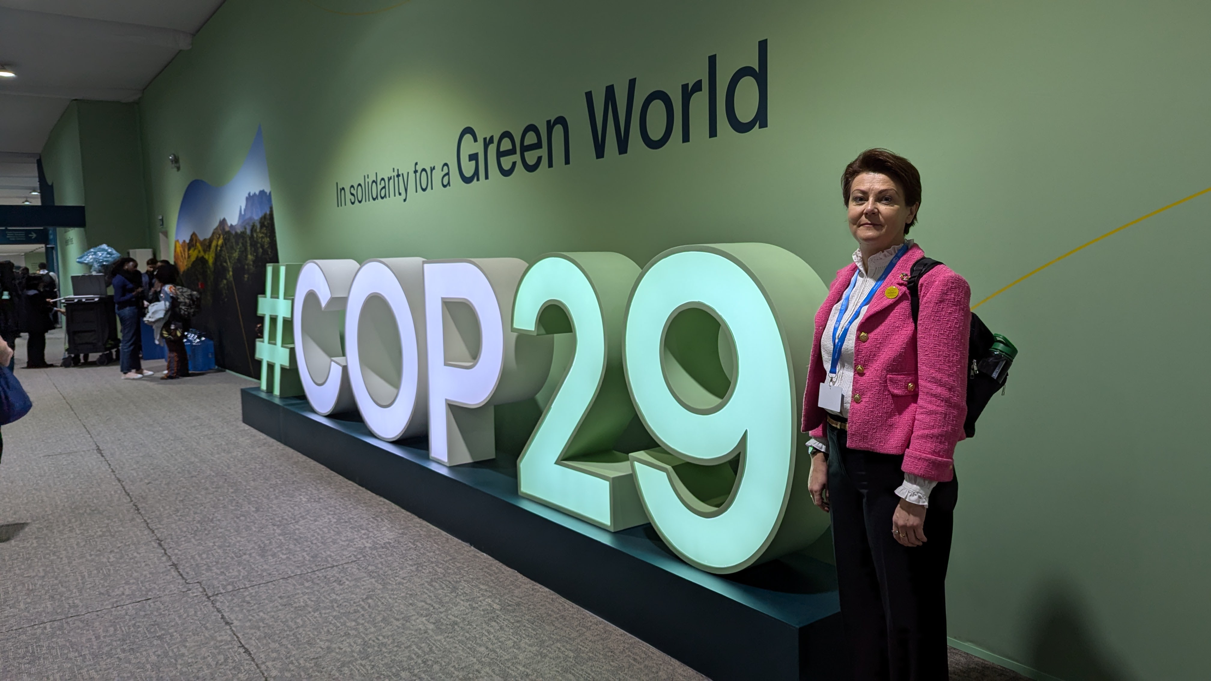 Image of Elena next to a COP29 sign.