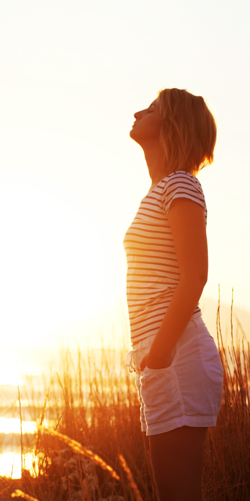 Picture of person stood outside at sunset taking a deep breathe