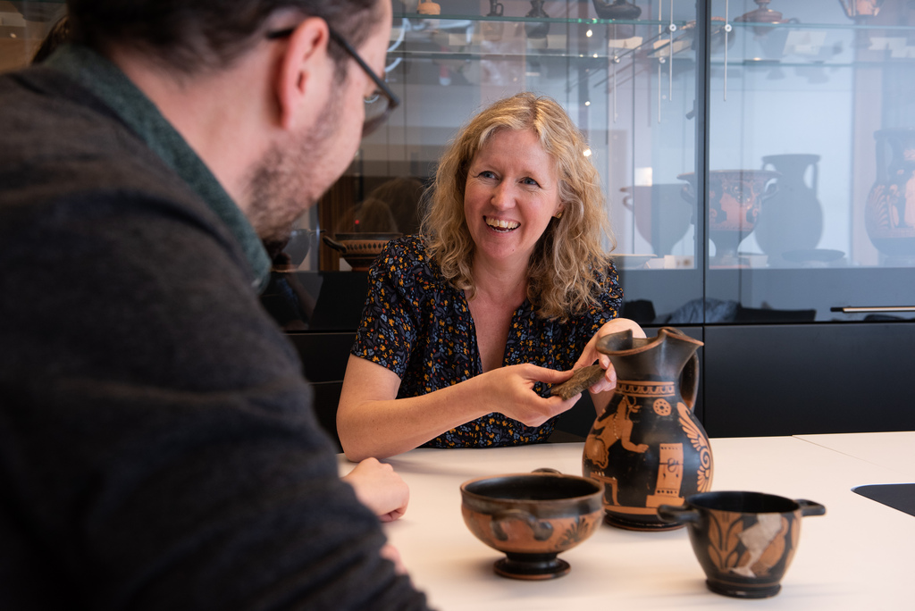 Two people examining ancient greek pottery