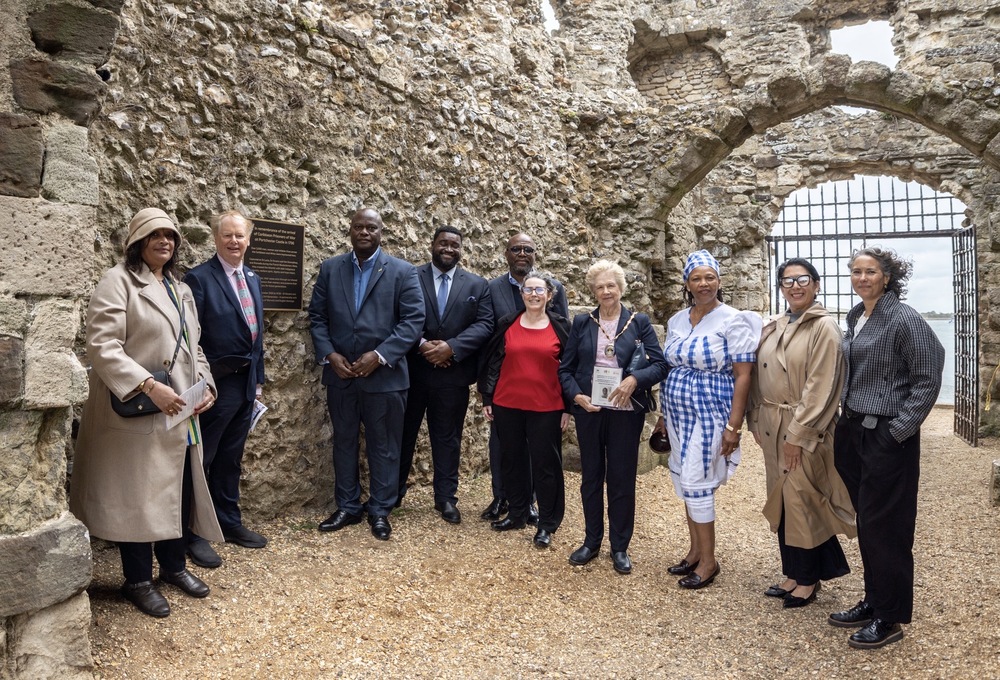 10 people standing facing camera in Portchester castle in front of plaque