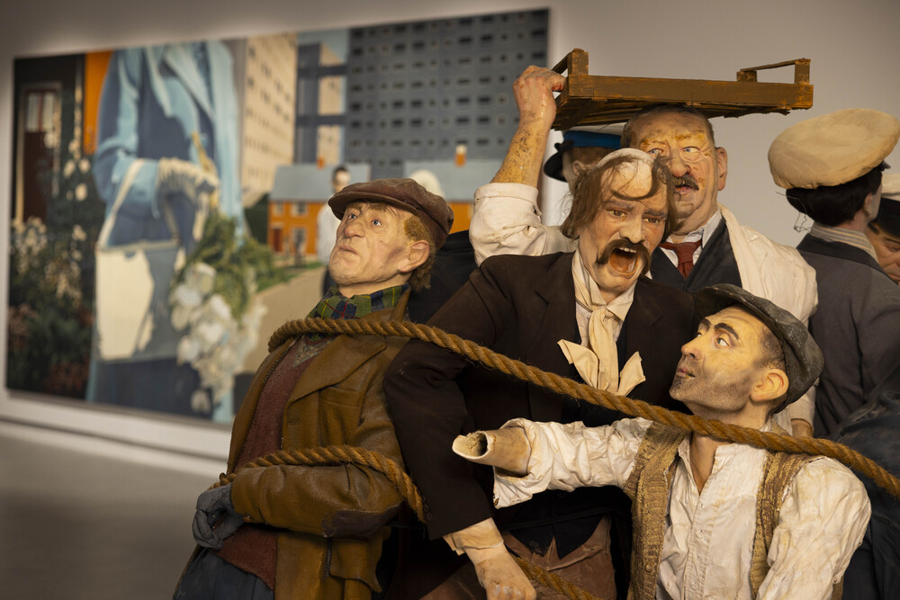 a sculpture artwork of men roped together