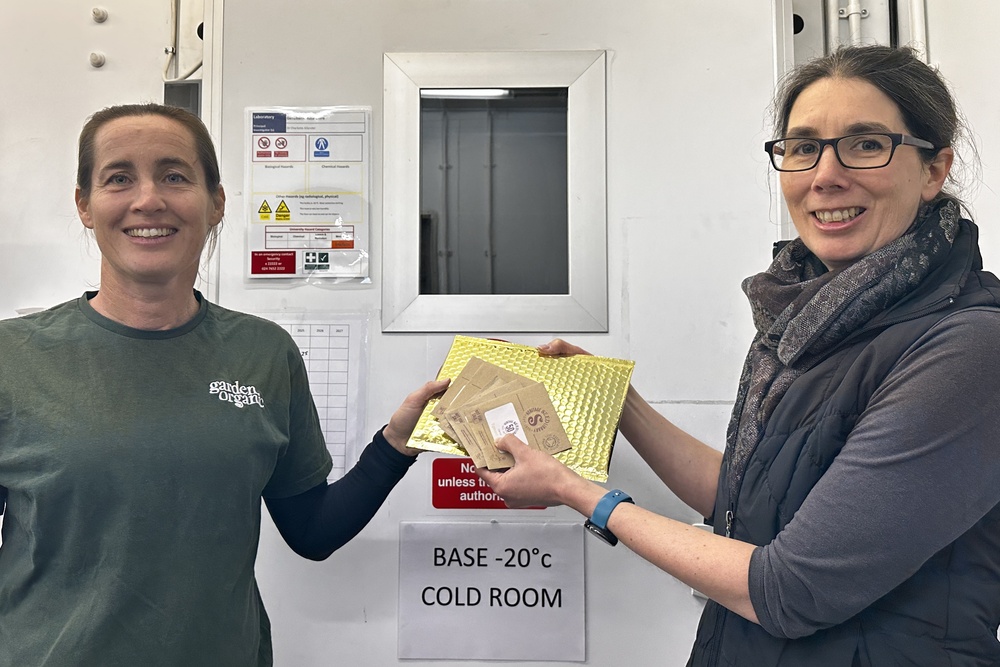 A golden seed packets being handed to Dr Charlotte Allender, head of UKVGB, by Garden Organic seed officer Lucy Shepherd