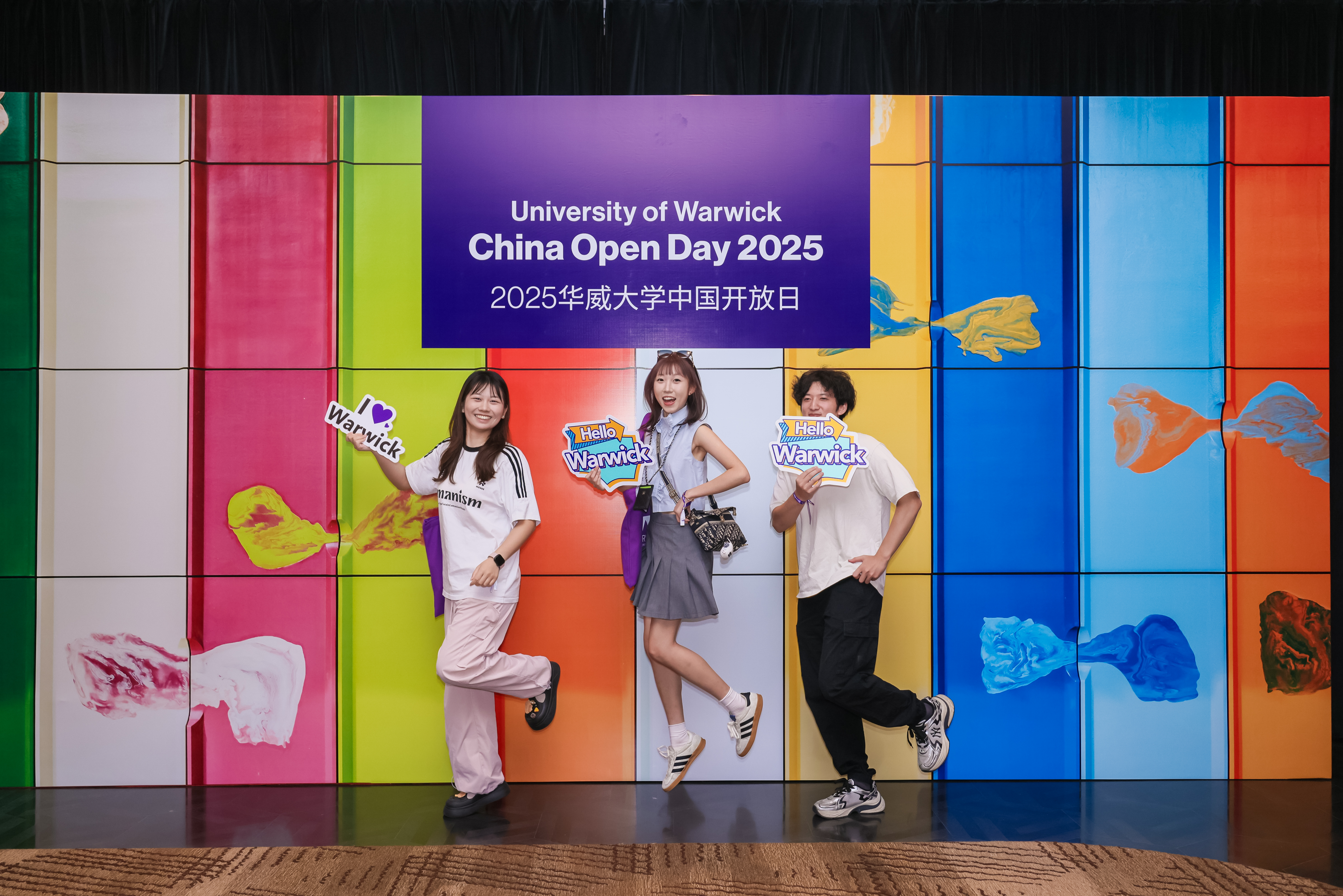 Students at China-Warwick Open days stood in front of bright, multi-coloured wall. 