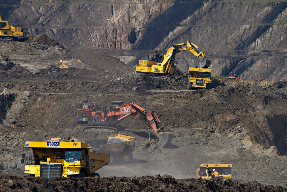 multiple diggers and dumpers trucks working a large open cast mine