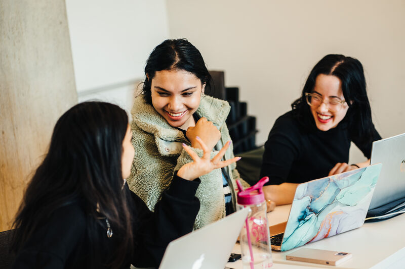 3 female students talking over their laptops