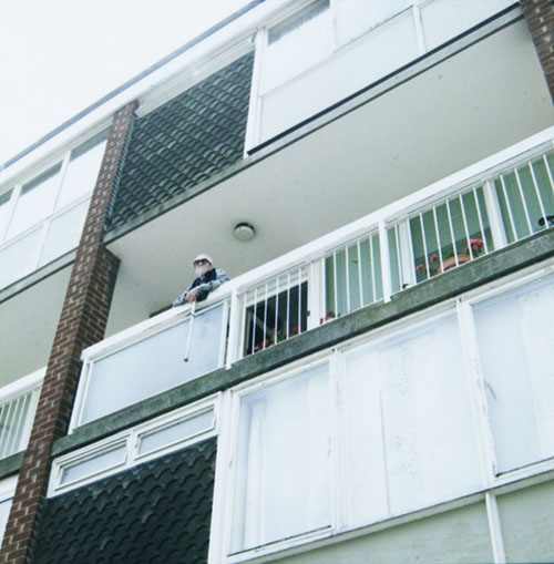 A man looks out from his balcony