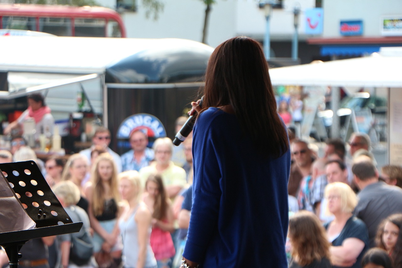 person on a stage with a mic with a crowd in front ot them