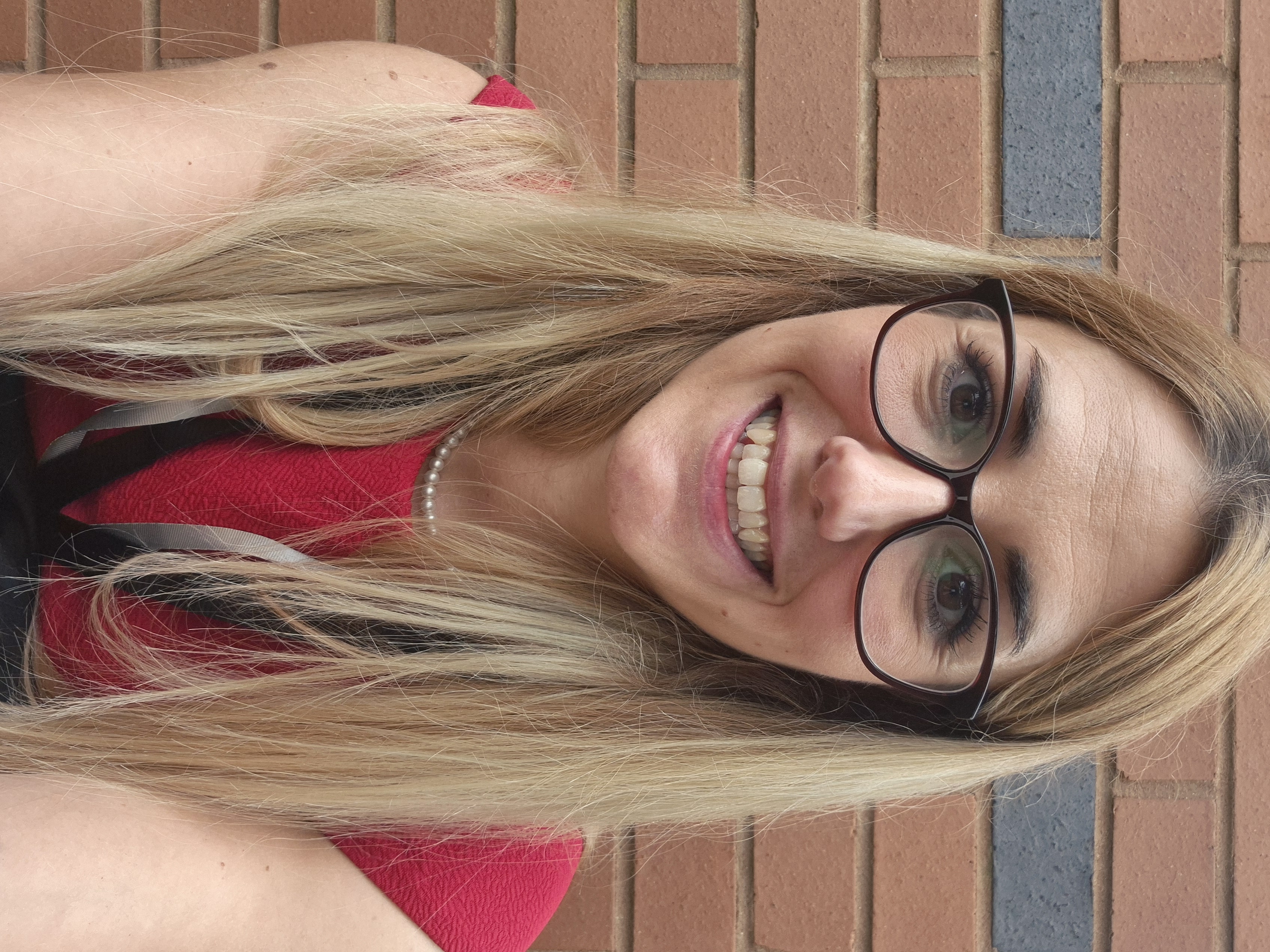 Woman with blonde hair and glasses in a red dress 