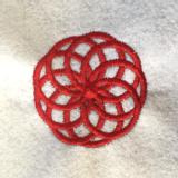 Red stitching on a white felt fabric background. The stitching is very thick and made up of several circles overlapping each other, joined at the centre and making a larger circular shape. 