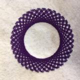 Purple stitching on a white felt fabric background. The lines of stitching create a ring with several small pints or corners in it. 