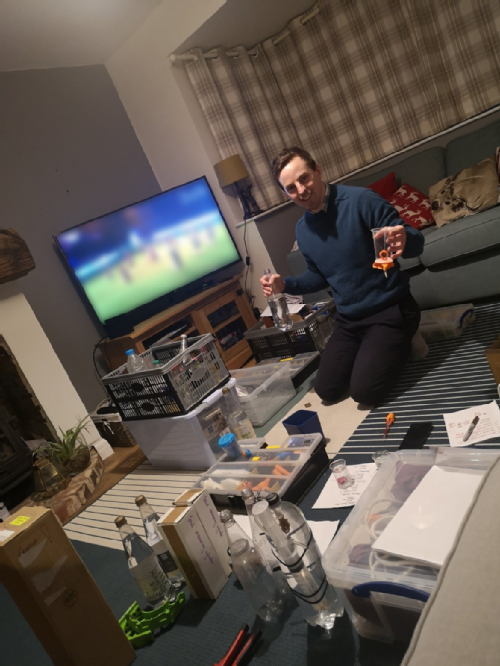 Phil is sat in his living room surrounded by piles of boxes of kit for British Science Week activities.