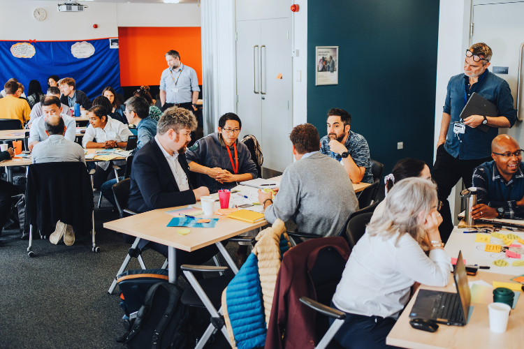 People sat around tables, discussing thoughts about sustainability research