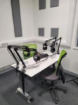Rodecaster pro, 4 microphones on extending arms, with 4 headphones, and the table is moved out to allow 4 people to sit around it.