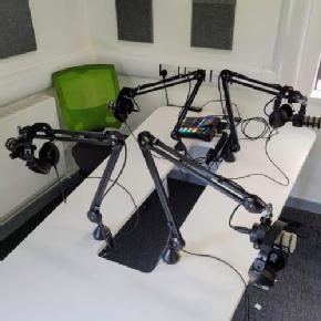 Podcasting equipment closeup showing 4 mics, headphones and stands and the rodecaster