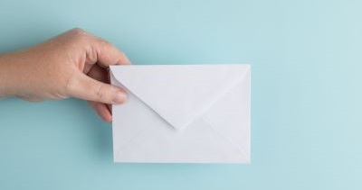 Image of hand holding an envelope on a light blue background