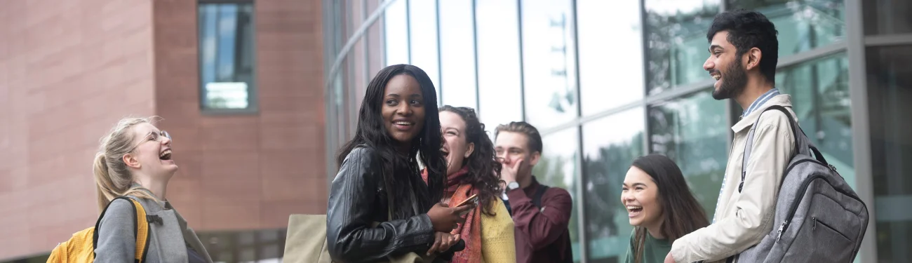 Students standing on campus laughing together.