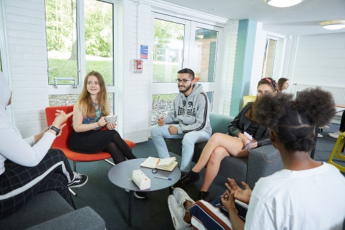 Students gathering and chatting together in shared area within residence