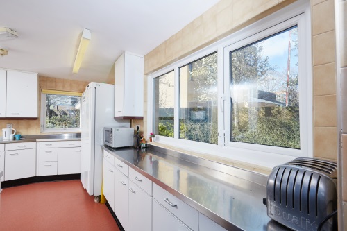 Kitchen showing fridge, toaster, work surface, plentiful cupboard space and windows