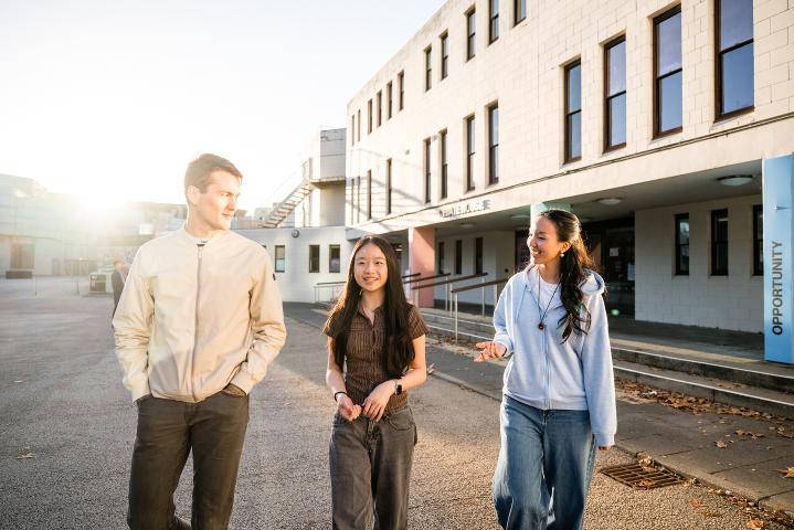 Three students walking outside Senate House on campus