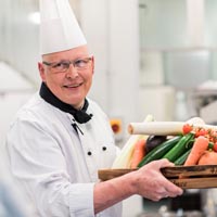 Chef carrying tray of vegetables