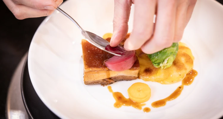 Chef plating up food on a white plate