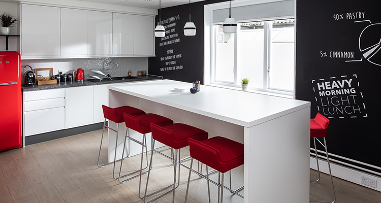 A small kitchen-style event room with four people talking around a table