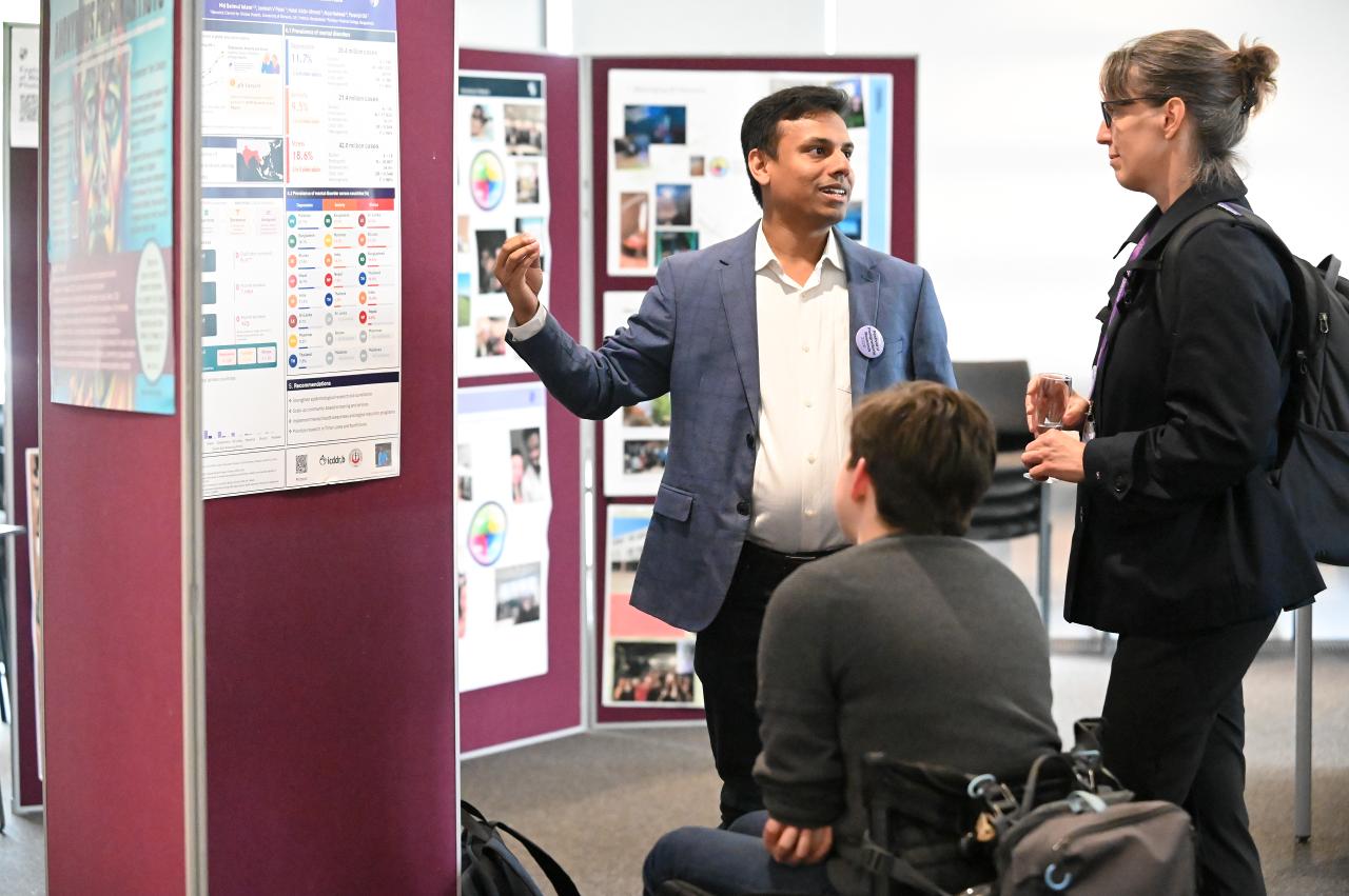 Three PGR students discussing a poster display