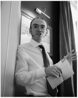 Pierre in a white shirt and holding papers 