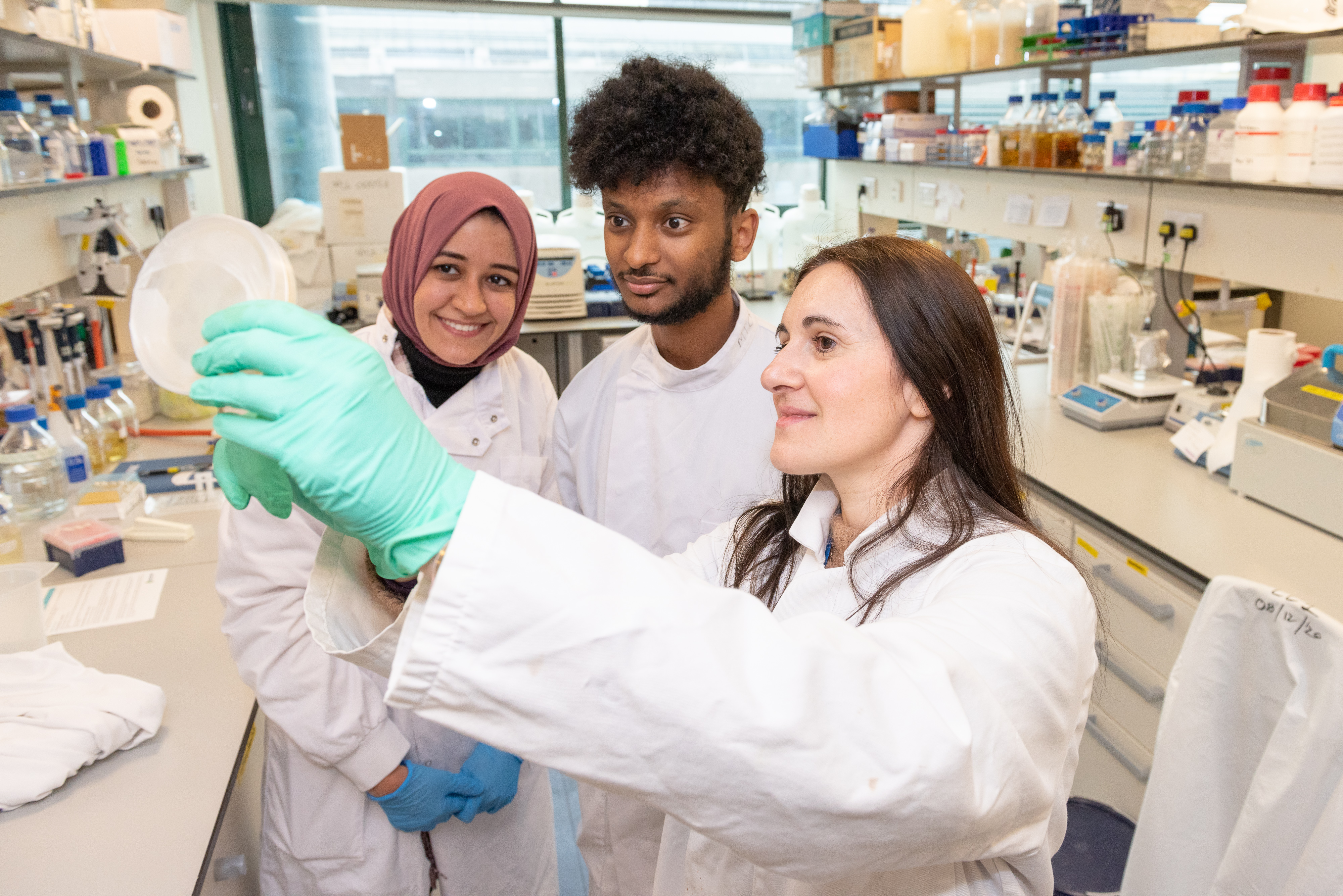 Two students of colour in the lab with a teacher