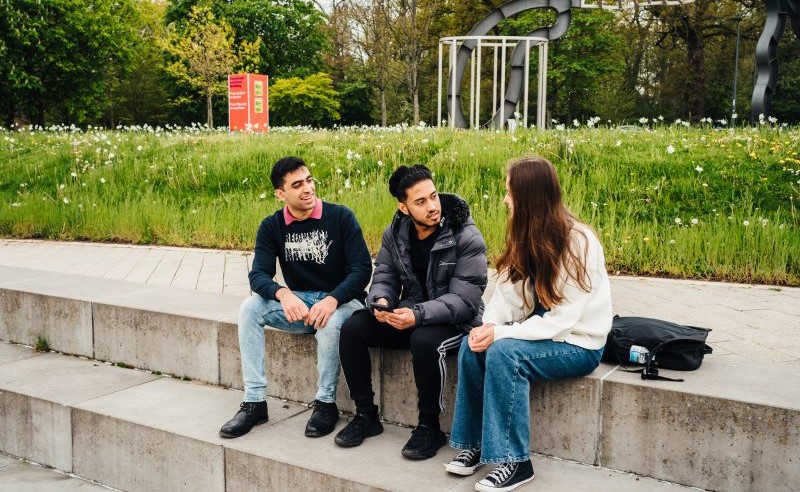 A group of three students chat in the piazza.