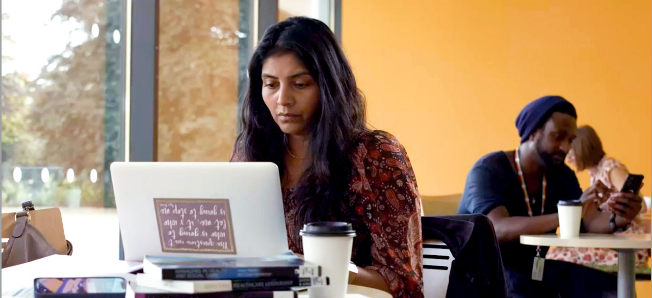 Image of a woman studying ina cafe with a laptop and coffee