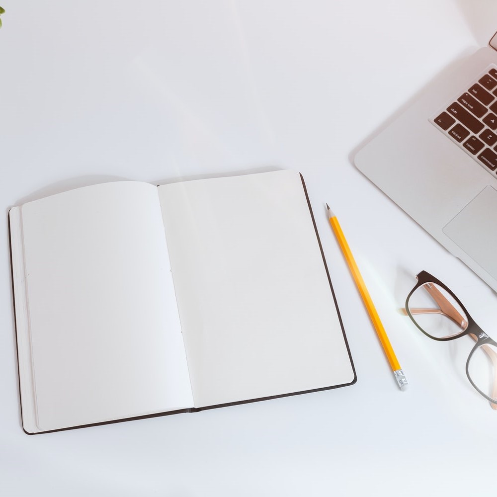 Empty notebook with pencil, glasses and keyboard