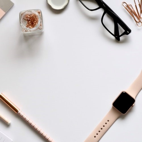 Desktop with glasses, watch, pens and paperclips