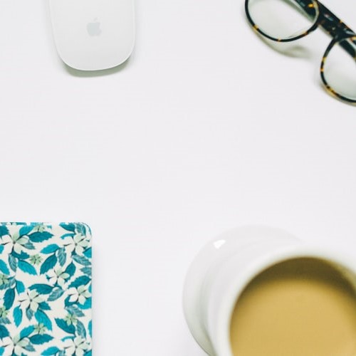 White surace with coffee, glasses, mouse and notebook