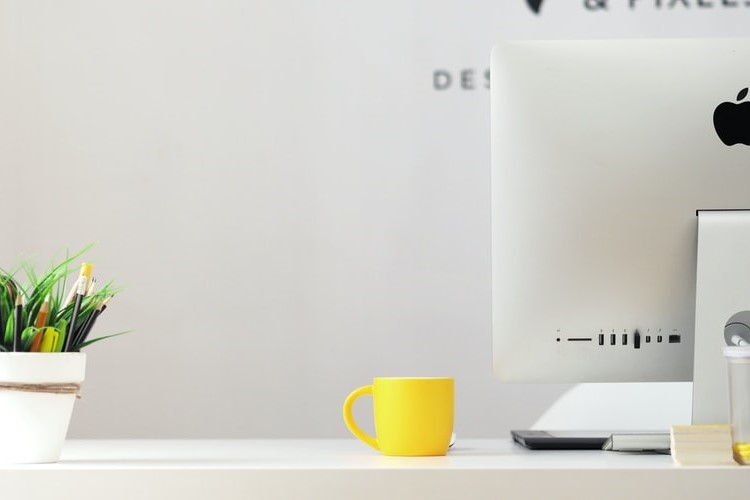 Desktop with yellow mug, monitor and plant