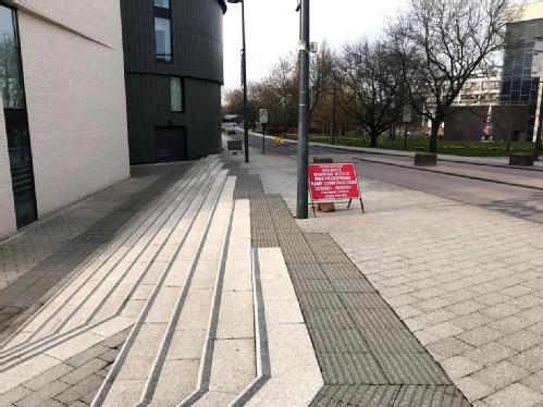 existing tapered stairs with tactile paving and red signs showing location