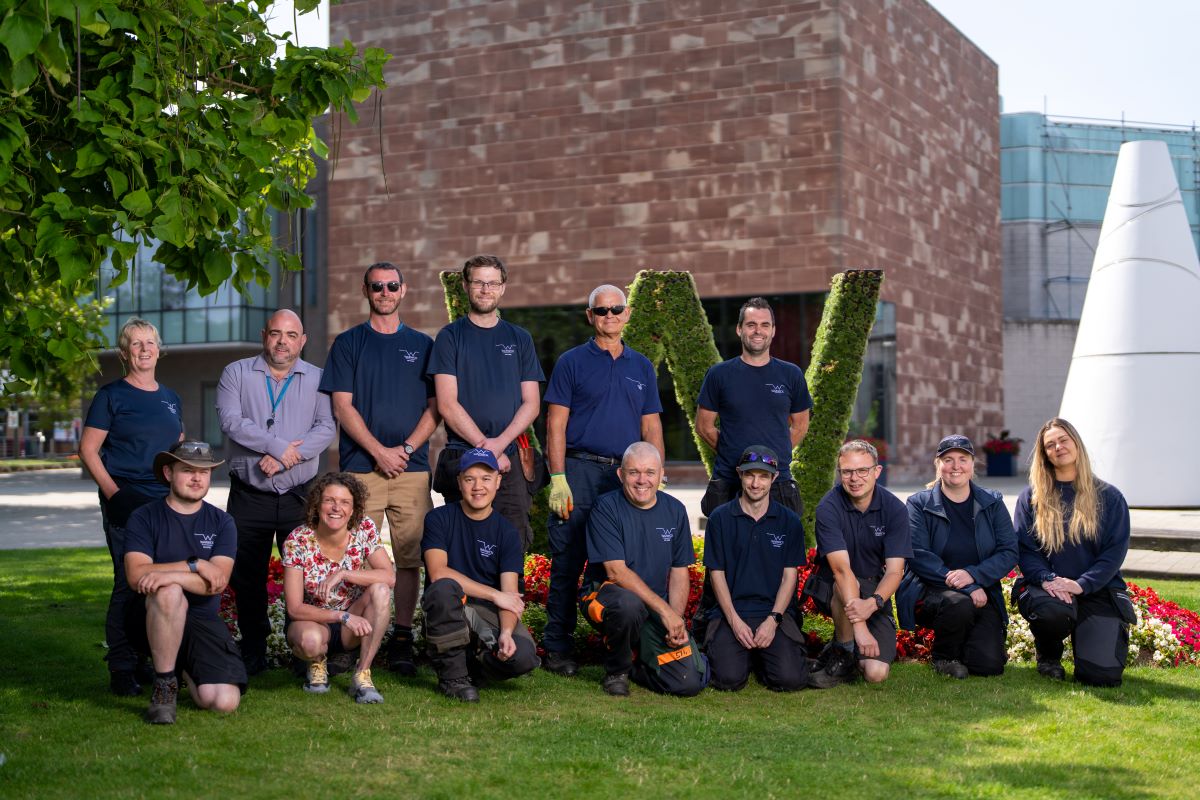 14 members of staff lined up outside the big W on Senate House lawn
